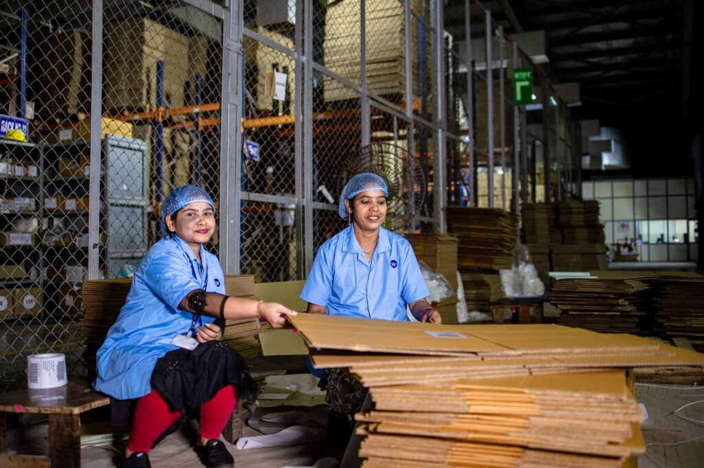 Workers in uniforms packing goods into cardboard boxes