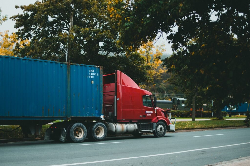 Red truck transporting a blue cargo container on the road