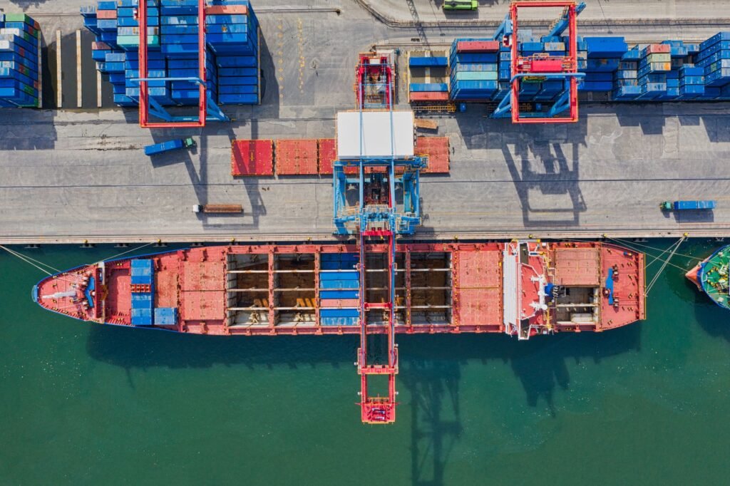 Container ship loading at a port terminal with cranes, aerial view