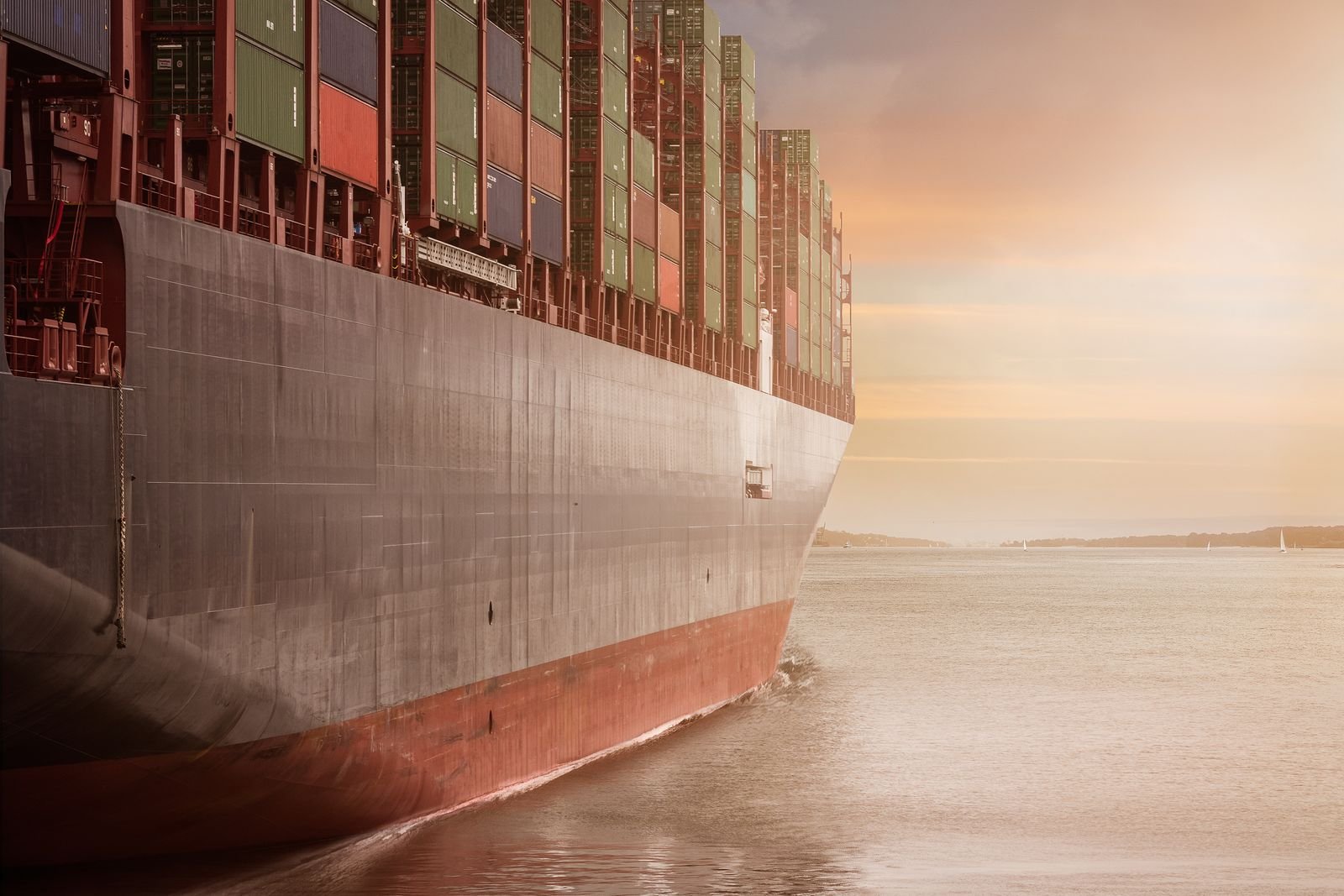 Container ship hull and stacked containers at sunset